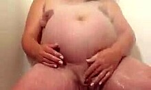 ¡Una mujer embarazada enorme se masturba seductoramente bajo la ducha! ¡No te pierdas esta escena caliente!