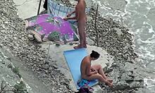 Mörkhårig amatör i nyanser är naken på en strand