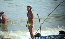 Wanita cantik tanpa atasan menunjukkan payudaranya yang kencang di pantai nudis