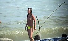 Wanita cantik tanpa atasan menunjukkan payudaranya yang kencang di pantai nudis
