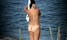 Nudista de peitos naturais mostra seu corpo em uma praia de nudismo deserta
