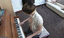 Hravá brunetka s živými prsy hraje na klavír nahoře bez