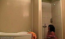 La mujer con voluptuosa se relaja debajo de una ducha y es observada