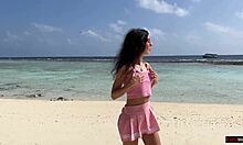 Прелепа девојка пиша под златним тушем на плажи на Малдивима